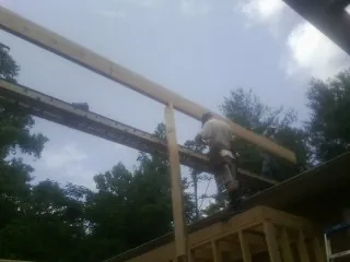 Carpenter setting a ridge beam over a new addition frame — Ice Dam Removal by Roofing Brothers in Hamlin
